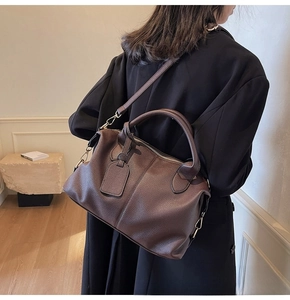 Deep brown litchi grain leather Boston bag shown with detachable strap on model