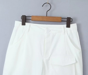 Detailed view of white cotton twill cargo pants with functional side pockets and waistband