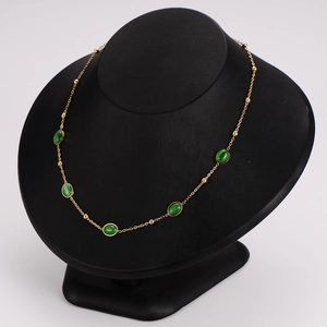 Vintage stainless steel jewelry set with oval green emerald stones on a black bust display