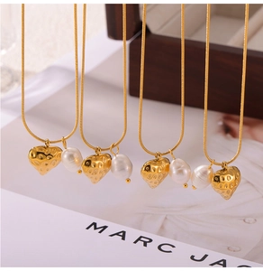Détail de quatre pendentifs cœur et perle baroque sur des chaînes serpent dorées