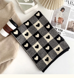 Close-up of knit heart pattern on black and white checkered scarf for winter