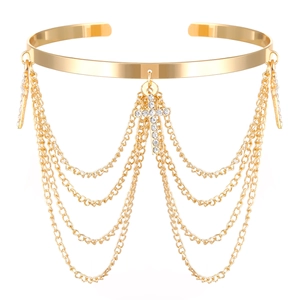 Macro detail of golden upper arm bracelet with tiered chains and crystal cross charms