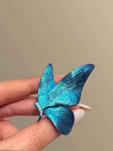 Macro detail of blue butterfly earring with etched metal texture and sparkling crystals