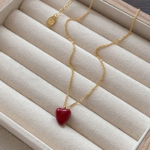 Macro shot of gold necklace with red heart pendant in a beige luxury jewelry box