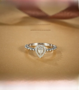 Close-up of S925 silver pear-shaped heart ring with micropave stones on gold silk