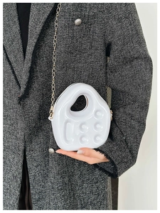 Close-up of white PVC jelly bag with gold chain strap worn over tweed jacket
