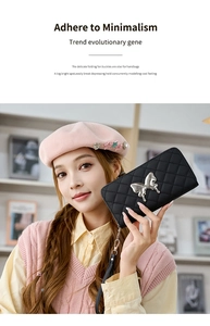 Detail of black quilted long wallet with silver bow clasp held by a fashion model