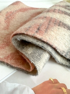 Gros plan de la texture douce d'une écharpe à carreaux beige rose et grise