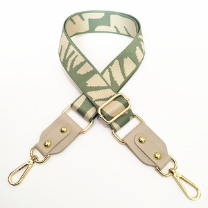 Detailed view of green and beige woven adjustable wide canvas bag strap with gold metal hooks