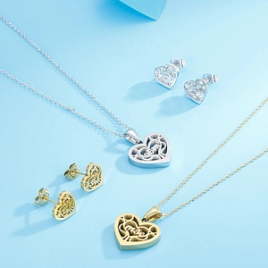Détail de colliers et boucles d'oreilles en forme de cœur évidé en finitions or et argent