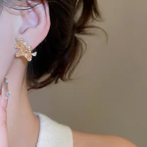 Close-up of 18k gold plated unicorn stud earring with shimmering crystals on ear