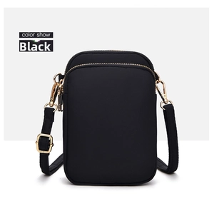 Front view of black nylon crossbody phone bag with multi-layer zippers and gold hardware