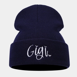 Detailed view of white Gigi embroidery on navy blue knit beanie with ribbed texture