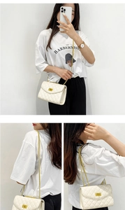 Detail of white quilted crossbody bag with gold chain strap and metal lock closure