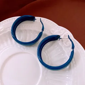 Deep blue enamel C-shape hoop earrings displayed on a vintage white ceramic plate