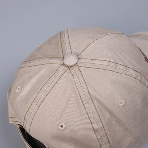 Detailed macro view of the beige cotton baseball cap crown with dark brown contrast stitching