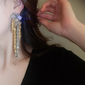 Detail of luxury long tassel earrings with sparkling rhinestones and golden leaf accents