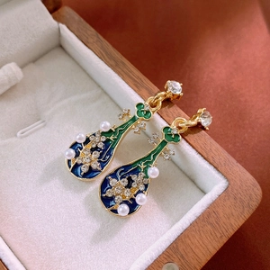 Macro detail of pipa lute earrings with blue enamel, faux pearls and sparkling crystals