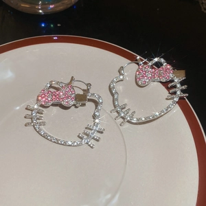 Macro shot of silver cat stud earrings with pink and white crystal rhinestones on a ceramic dish