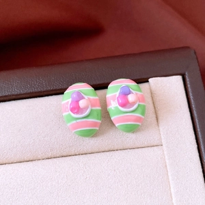 Macro view of striped oval stud earrings with colorful beads in a jewelry box