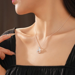 Gros plan d'un mannequin portant un collier avec pendentif cheval à bascule argenté minimaliste