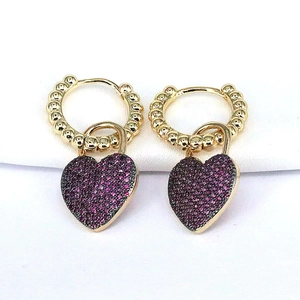 Macro view of heart-shaped zircon drop earrings with gold hoops and purple inlay