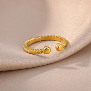 Detail of twisted rope gold ring with spherical ends on elegant silk fabric background