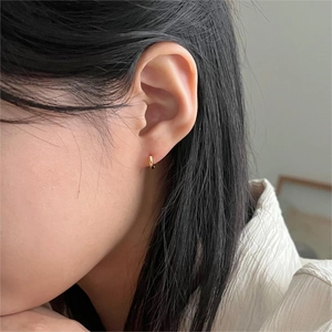 Close-up of minimalist gold hoop earrings on model featuring a polished round design