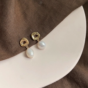 Detail of baroque pearl earrings featuring irregular hammered 18K gold-plated metal texture