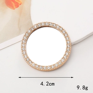 Detail of a 4.2cm round gold makeup mirror with sparkling white rhinestones on the frame