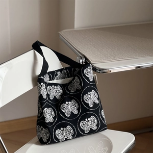Detailaufnahme der weißen Schmetterlingsstickerei auf einer schwarzen Stofftasche