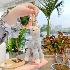 Close-up of a soft light grey alpaca plush pendant with silver metal keychain ring