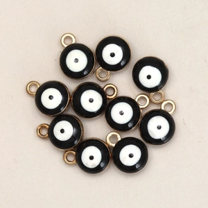 Detailed view of multiple 8mm black and gold evil eye charms for DIY jewelry making