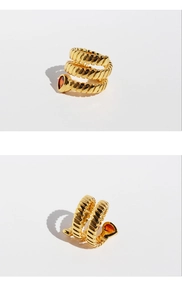 Macro detail of golden triple-layered snake ring featuring red teardrop zircon gemstone