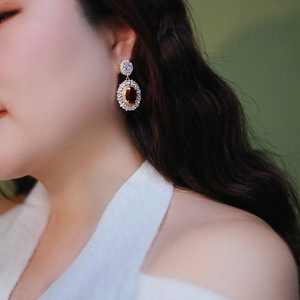 Detailed close-up of luxury vintage flower earrings with red ruby stones on a model's ear