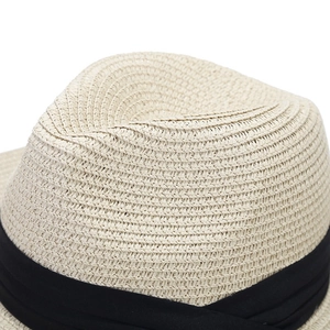 Close-up of the woven texture and black ribbon detail on a beige Panama straw hat