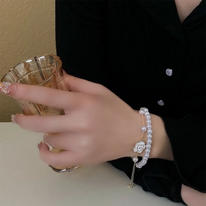 Close-up of double-layer camellia pearl bracelet with golden chain on model's wrist