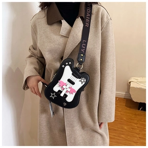 Detail of guitar-shaped crossbody bag with pink bat wings and star studs on cream coat