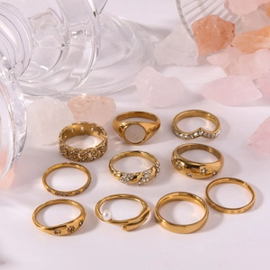 10-piece gold stainless steel ring set with pearls and crystals on minimalist white background