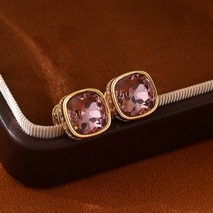 Macro de boucles d'oreilles carrées en cristal rose et base dorée sur cuir brun