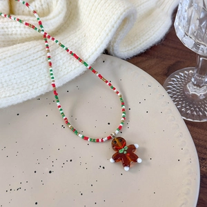 Close-up of a festive Christmas necklace with a gingerbread man pendant on a tray
