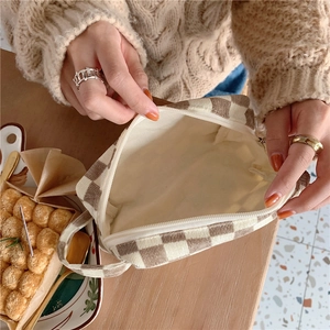 Vue détaillée d'une trousse à maquillage en velours côtelé à carreaux sur une table