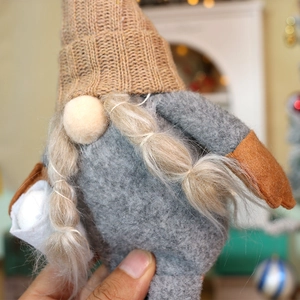Close-up of a Christmas gnome doll with a brown knit hat and long white braids