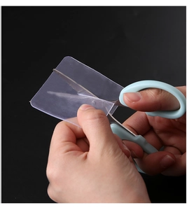 Close-up of cutting transparent double-sided adhesive tape with blue scissors