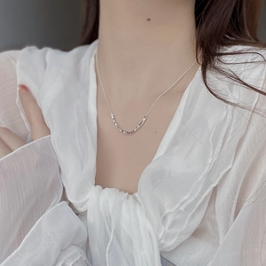 Close-up of minimalist 925 sterling silver necklace with geometric cube pendants on skin