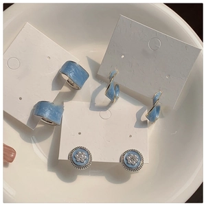 Detail of blue drip oil earrings including C-shaped, twisted and pearl flower styles