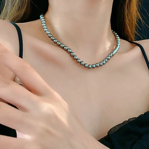 Detail of elegant dark grey pearl necklace worn by model on collarbone area