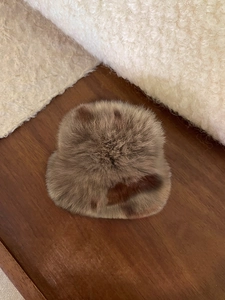 Gros plan d'une pince à cheveux en peluche avec motifs léopard sur socle en bois