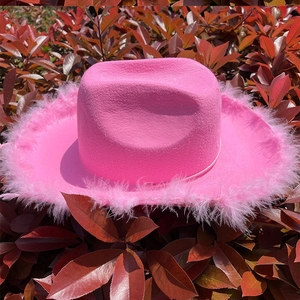 Primer plano de sombrero vaquero rosa brillante con corona hendida y borde de plumas