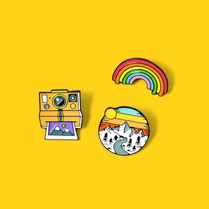 Set of 3 cartoon enamel pins featuring a retro camera, rainbow, and scenic mountain landscape